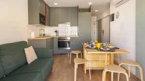 A compact kitchen with a dining area, a green sofa, and a small table with chairs. - B93 - Miralvor 2 Bed Apartment in Alvor (Alvor)