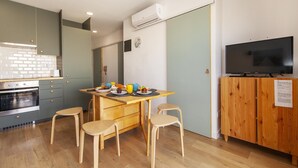 A modern kitchen with a dining area, wooden cabinets, a TV, and a built-in oven. - B93 - Miralvor 2 Bed Apartment in Alvor (Alvor)