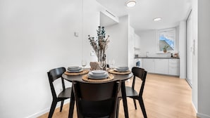 Ein moderner Essbereich mit einem runden Tisch, schwarzen Stühlen und einer Blumenvase.