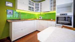 A compact kitchen with white cabinetry, a built-in oven, and a green backsplash.