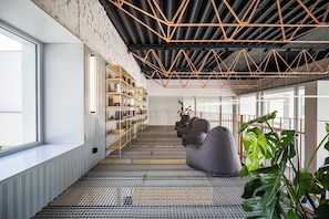 A modern interior with a high ceiling, exposed ductwork, and a seating area with bean bags.