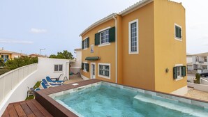 Un bâtiment jaune doté d’une piscine, d’une terrasse et d’un espace salon couvert.