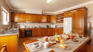 Une cuisine avec des meubles en bois, un réfrigérateur et une table à manger mise pour le petit-déjeuner.
