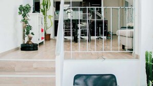 A modern interior with a staircase, a black chair, and potted plants. - Mi Apartments - Old Town Heart-Terrace&Castle View (Bratislava - Old Town)