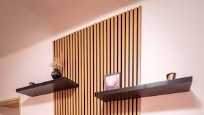 Una sala de estar moderna con una televisión de pantalla plana montada en una pared de listones de madera, una mesa de centro de madera y dos estantes flotantes.