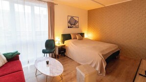 Una habitación de hotel con cama, sillón, pequeña mesa y sofá.