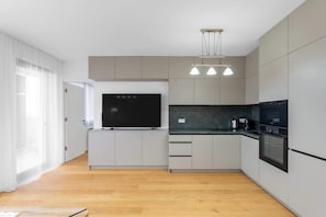 Eine moderne Küche mit Flachbildfernseher, Backofen und Pendelleuchten.