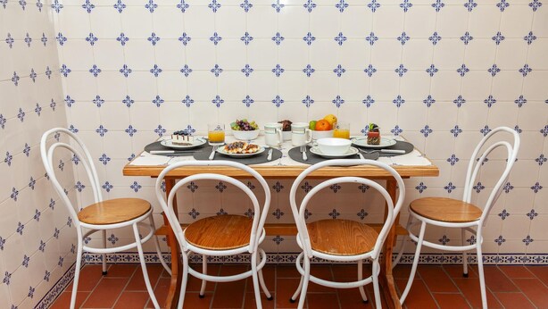 Une table à manger avec quatre chaises, entourée de carreaux décoratifs et posée sur un sol carrelé.