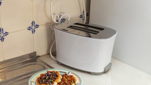 Un grille-pain blanc posé sur un plan de travail de cuisine, avec une assiette de gaufres à côté.