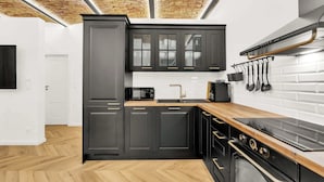 Una cucina moderna con mobili scuri, un piano di lavoro in legno, un forno a microonde, un lavello e un piano cottura.