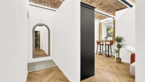 Un interno moderno con pavimento in legno a spina di pesce, pareti bianche, una parete d'accento nera e soffitto in mattoni.
