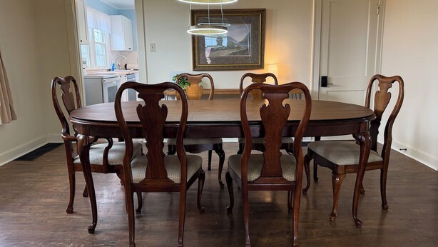 A dining room with a round table, six chairs, and a modern pendant light. - Lucky Horseshoe Farmhouse (Wilmington)