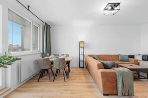 Ein modernes Wohnzimmer mit Essbereich, einer Couch und einer Stehlampe.