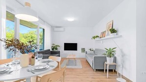Un salon moderne comprenant un coin repas, un téléviseur à écran plat et des plantes en pot.
