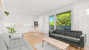 Un salon moderne avec un canapé gris, une table basse en bois et un coin repas comprenant une table et des chaises blanches.