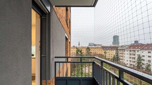 Ein Balkon mit Blick auf eine Stadtlandschaft, darunter eine Kirche und Wohnhäuser.