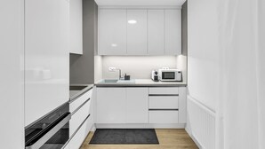 Eine moderne Küche mit weißen Schränken, einem Backofen, einer Mikrowelle und einem Spülbecken.