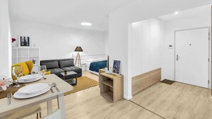 Ein modernes Wohnzimmer mit einer Couch, einem Esstisch und einer Lampe.