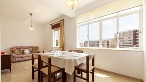 Un comedor con una mesa dispuesta para cuatro personas, un sofá y una ventana con vistas a la ciudad.