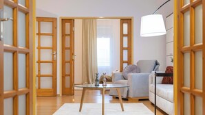 A room with a glass table, a sofa, a lamp, and wooden doors. - Your City Center Stylish & Spacious Apartment (Košice)