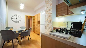 A modern kitchen with a gas stove, wooden cabinets, and a stone accent wall. - Your City Center Stylish & Spacious Apartment (Košice)