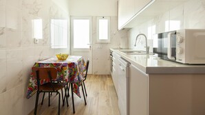Una cucina compatta con tavolo, sedie, forno a microonde e lavello.