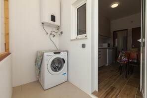 A laundry area with a washing machine, a small shelf with a device, and a window above it. - B101 - Abrotea Cozy 2 Bed Apartment in Lagos (Lagos)
