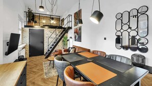 Uma área de refeições moderna com uma mesa preta, cadeiras de couro e uma escada que leva a um mezanino.
