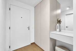 Un baño moderno con una puerta blanca, un espejo y un estante pequeño con un florero.