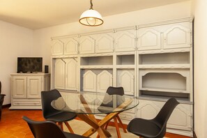 A dining area with a glass table and black chairs, white cabinetry with decorative moldings, and a hanging light fixture. - A72 - Praia da Luz Coast Flat (Praia da Luz)