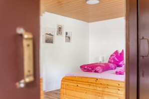 Una camera da letto con un letto di legno, una parete bianca e tre quadri incorniciati.