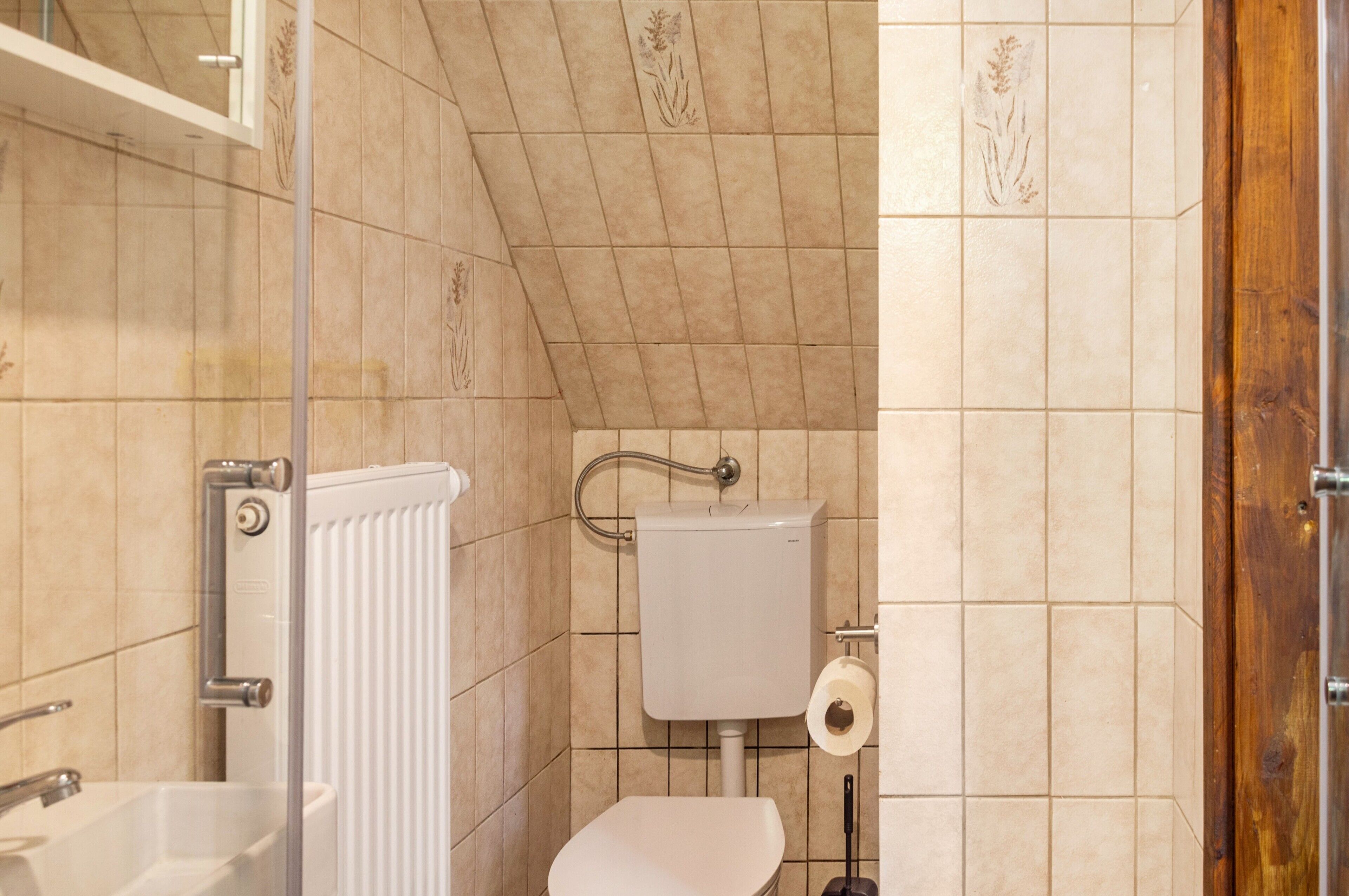 Une salle de bain équipée de toilettes, d’un lavabo, d’une douche et d’un radiateur.