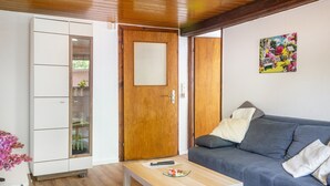 Ein Zimmer mit Holztür, einem blauen Sofa, einem weißen Schrank mit Glastüren und einem Bild an der Wand.