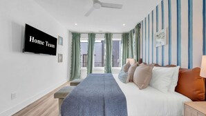 A hotel room with a bed, a TV, a window with curtains, and a view of the outside.