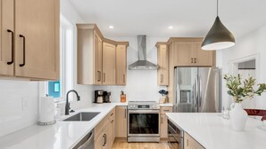 A modern kitchen with wooden cabinets, stainless steel appliances, and a white countertop.