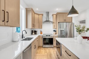 A modern kitchen with wooden cabinets, stainless steel appliances, and a white countertop. - 4BR Nashville Hideaway - Rooftop Views - Fire Pit (Nashville)