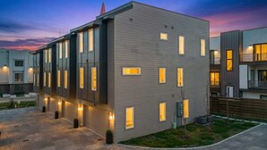 A modern multi-story residential building with a flat roof, multiple windows, and a well-lit exterior.