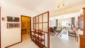 A hotel room with a traditional Japanese-style sliding door, a dining area with a green table, and a view of the city. - A02 - Casa Topazio in Quarteira (Quarteira)