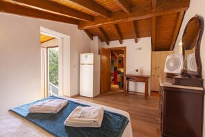 Un dormitorio con cama, techo de madera, una mesita, un espejo y una kitchenette.