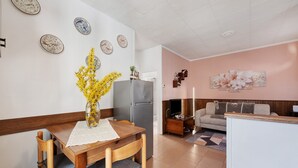 A compact living space with a dining table, chairs, a refrigerator, a sofa, and a TV.