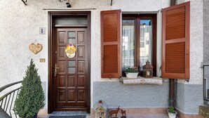 A wooden door with a heart-shaped decoration, a small house-shaped ornament, and a metal sculpture of a deer and a child.