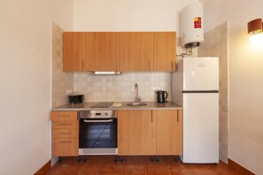 Uma cozinha compacta com armários de madeira, forno embutido, pia, cafeteira e geladeira branca.