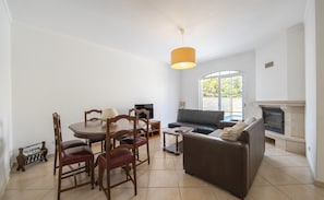 Una sala de estar con una mesa de comedor, sillas, un sofá, una chimenea y un televisor.