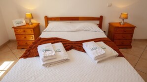 A neatly made bed with a brown throw blanket, two bedside tables with lamps, and a wall-mounted artwork.