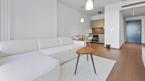 En moderne stue med en hvid sofa, et lille træbord og hængende lamper.
