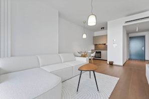 Ein modernes Wohnzimmer mit einem weißen Sofa, einem kleinen Holztisch und Pendelleuchten.
