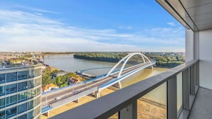 Un bâtiment moderne doté d’une façade en verre, d’un pont piétonnier et bordé par une rivière.