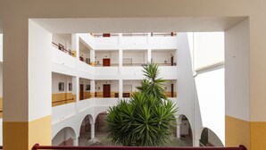 A multi-level atrium with a central plant, balconies, and a red handrail.