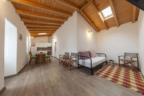 A room with a wooden ceiling, a bed, a dining table with chairs, and a kitchen area. - A28 - Castela Street Townhouse in Espiche (Praia da Luz)