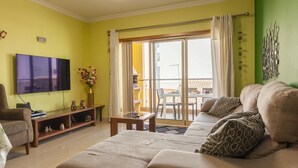 A living room with a sofa, TV, and a balcony with a table and chairs. - C08 - Ladeira do Convento 3 Bed Apartment in Lagos (Lagos)